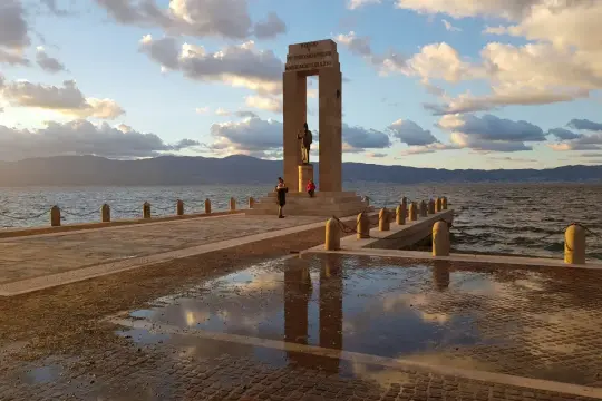 Un tramonto sul lungomare di Reggio Calabria, con il monumento ai caduti e le montagne sullo sfondo. Un luogo perfetto per scoprire cosa fare a Reggio Calabria.
