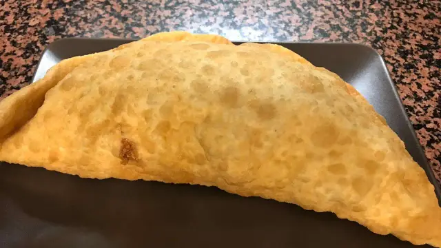 Una sfogliatella siciliana fritta zafferana, dorata e croccante, pronta per essere gustata.
