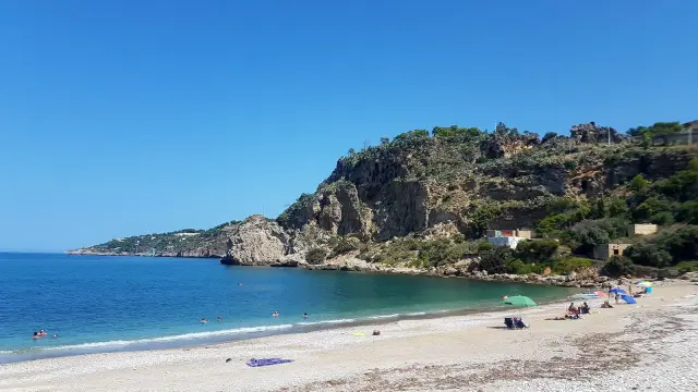 La spiaggia di San Cataldo a Terrasini, con le sue acque cristalline e la scogliera imponente, offre un rifugio sereno per godersi il sole.