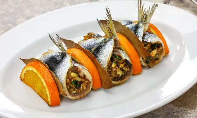 Sardine ripiene, un'esplosione di sapori mediterranei, tra le specialità siciliane salate. Arancia, alloro e un ripieno gustoso.
