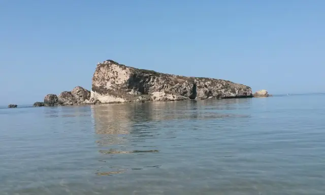 La Rocca San Nicola a Licata, imponente roccia calcarea che emerge dal mare cristallino, sotto un cielo azzurro.