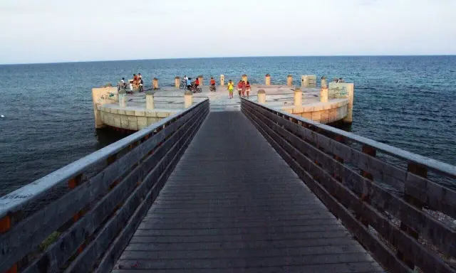 Passeggiata sul lungomare di Avola di sera, con persone che si godono la vista dal molo circolare.