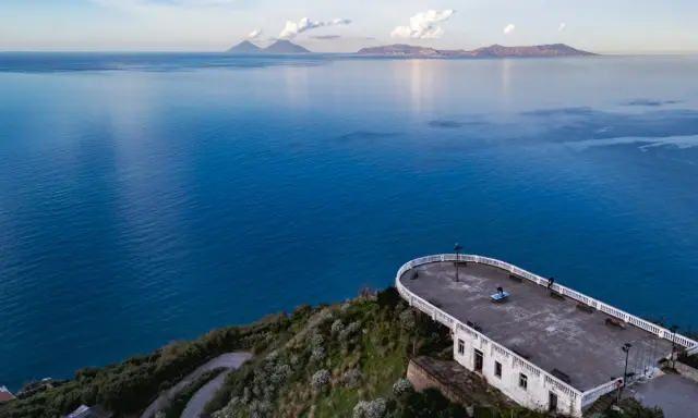 La guardiola Piraino domina il mare blu cobalto. All'orizzonte, le isole Eolie emergono dalla foschia.