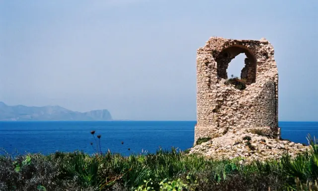 Torre saracena in rovina, un luogo suggestivo da scoprire a Terrasini, con il mare blu e le montagne sullo sfondo.