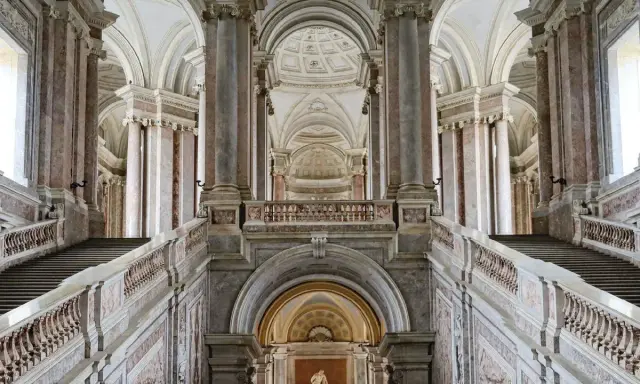 Magnifici interni della Reggia di Caserta: scalinate imponenti, marmi pregiati e volte maestose creano un'atmosfera regale.