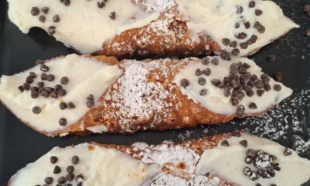 Cannoli siciliani, un classico di cosa si mangia in Sicilia: croccanti cialde ripiene di crema e gocce di cioccolato.
