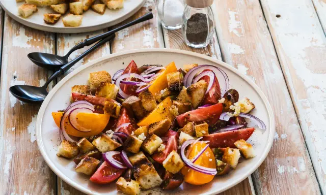 Un piatto di panzanella siciliana con pomodori, cipolla rossa e crostini croccanti.