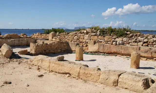 Rovine antiche a Mozia, cosa vedere: resti di mura e colonne di pietra con il mare sullo sfondo sotto un cielo azzurro.