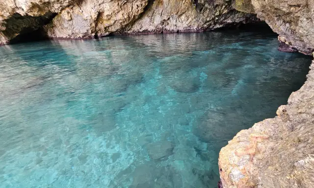 Acque cristalline nella baia di San Cataldo, con rocce calcaree che creano un'atmosfera suggestiva.