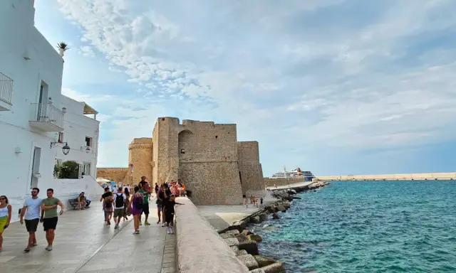 Passeggiata serale a Monopoli: il castello, il mare azzurro e una nave da crociera.