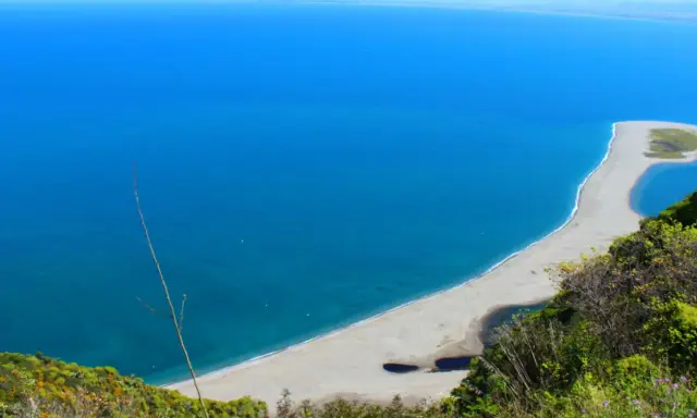 La **marinello spiaggia** si estende in un arco di sabbia chiara, lambita da un mare azzurro intenso. Laghi interni e vegetazione rigogliosa incorniciano questo angolo di paradiso.