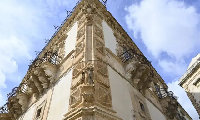 Angolo del palazzo Beneventano a Scicli, con balconi in ferro battuto e sculture barocche.
