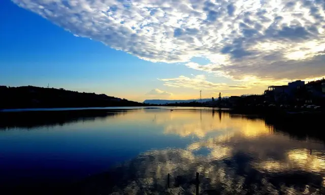 Tramonto sui Ganzirri, con cielo nuvoloso e riflessi dorati sull'acqua. Un luogo incantevole da esplorare.