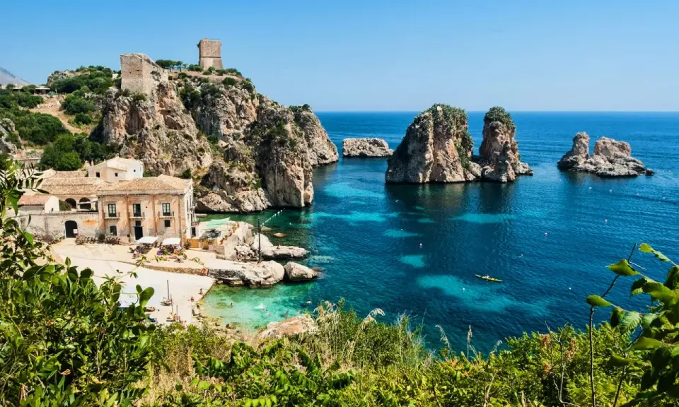 Baia con faraglioni e torri antiche, ideale per scoprire come arrivare a Scopello e godersi il mare cristallino.