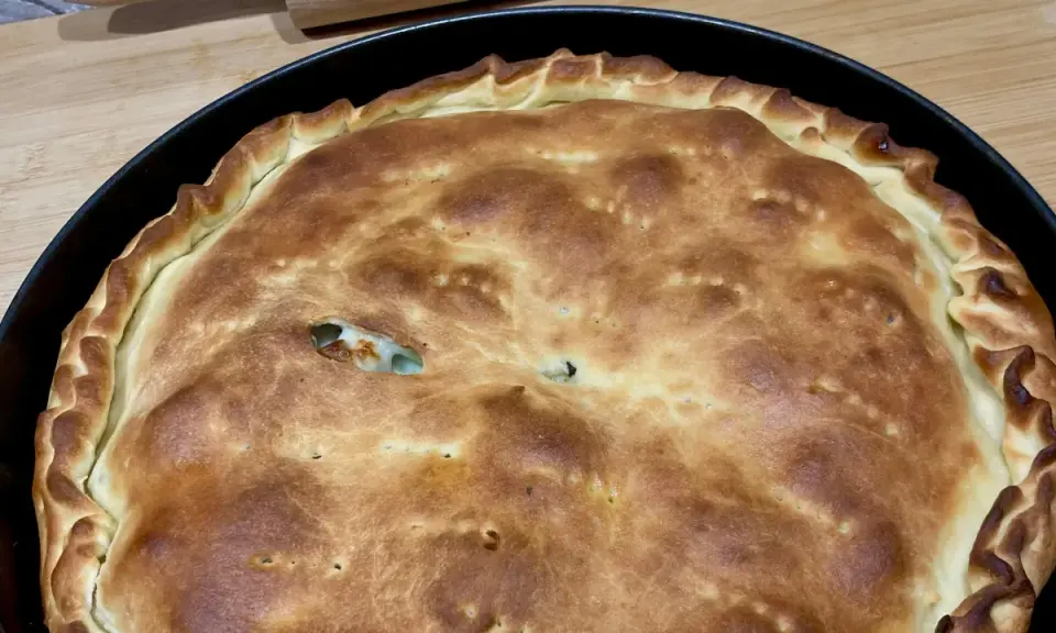 Schiacciatella pane dorata e fragrante, appena sfornata in teglia, con un ripieno invitante che fa capolino da una fessura.