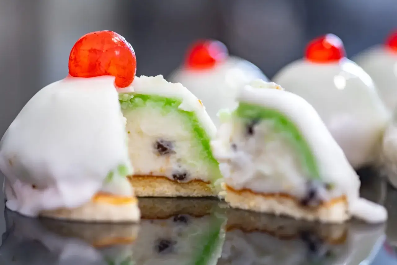 Dolci siciliani con glassa bianca, ripieno verde e canditi, un assaggio dei piatti tipici siciliani.
