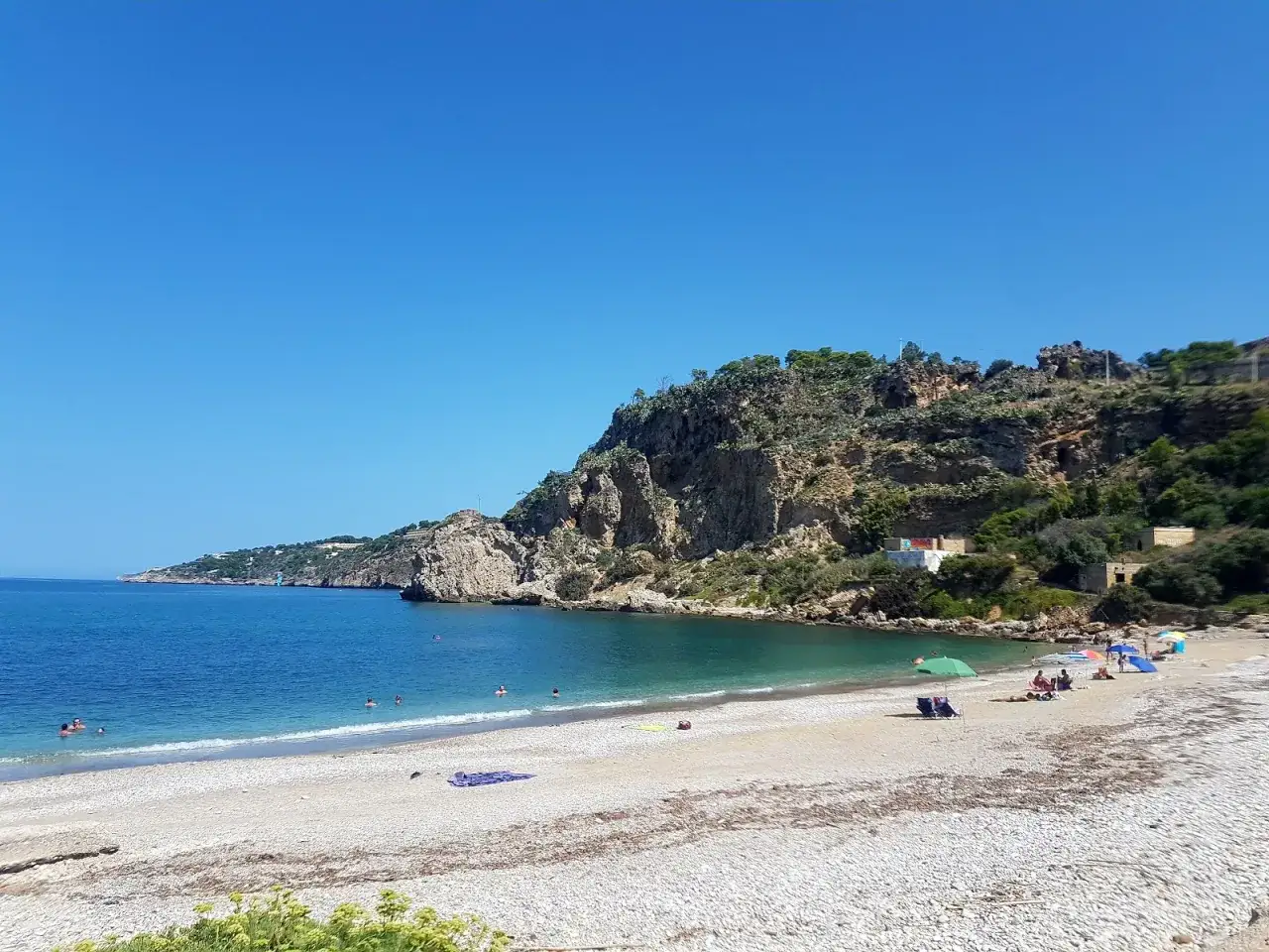 La baia di San Cataldo, con le sue acque cristalline e la spiaggia di ciottoli, invita al relax sotto il sole siciliano.