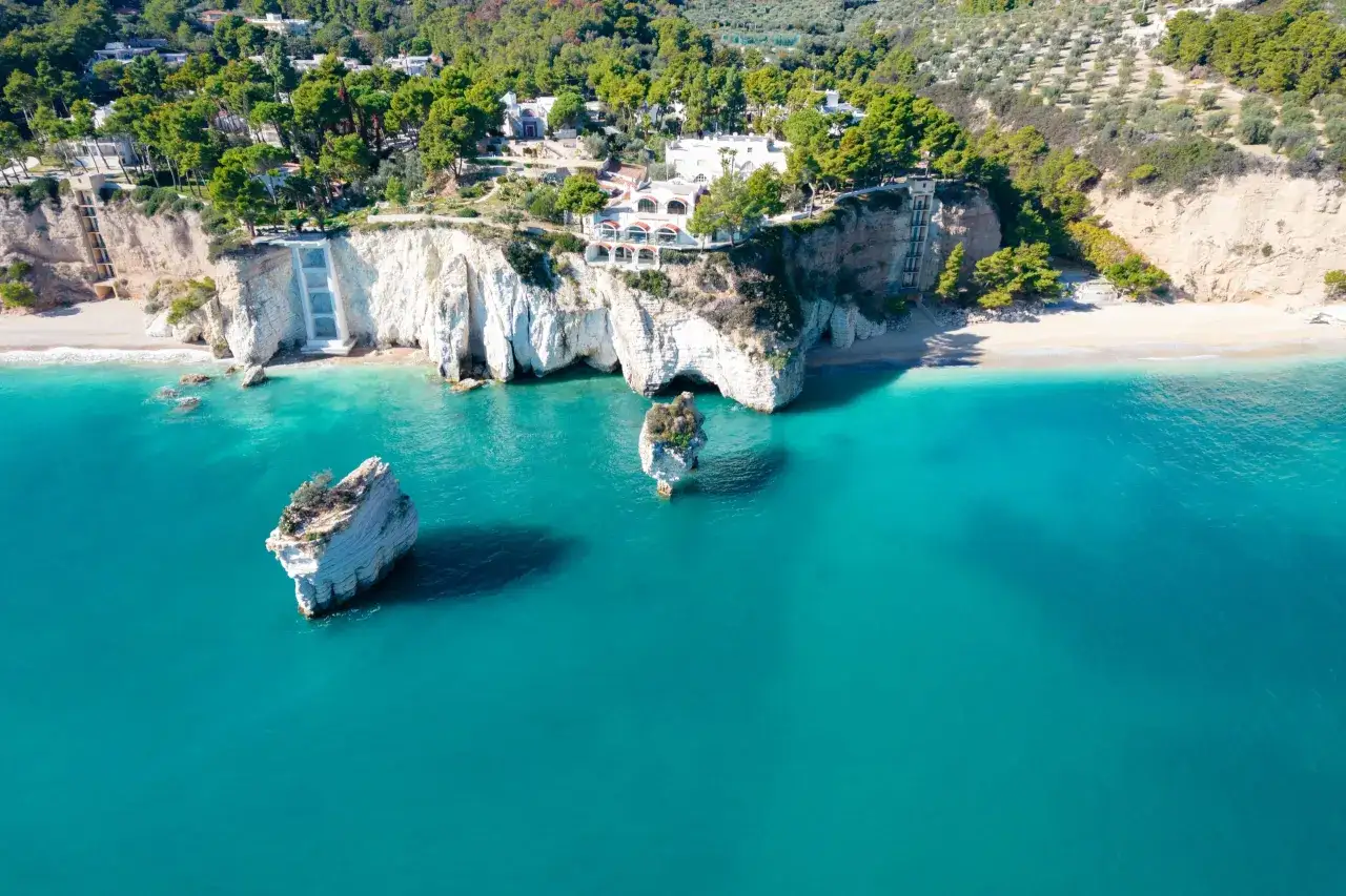 Scogliere bianche a picco sul mare turchese, con rocce isolate e vegetazione lussureggiante. Un vero gioiello tra le spiagge più belle della Puglia.