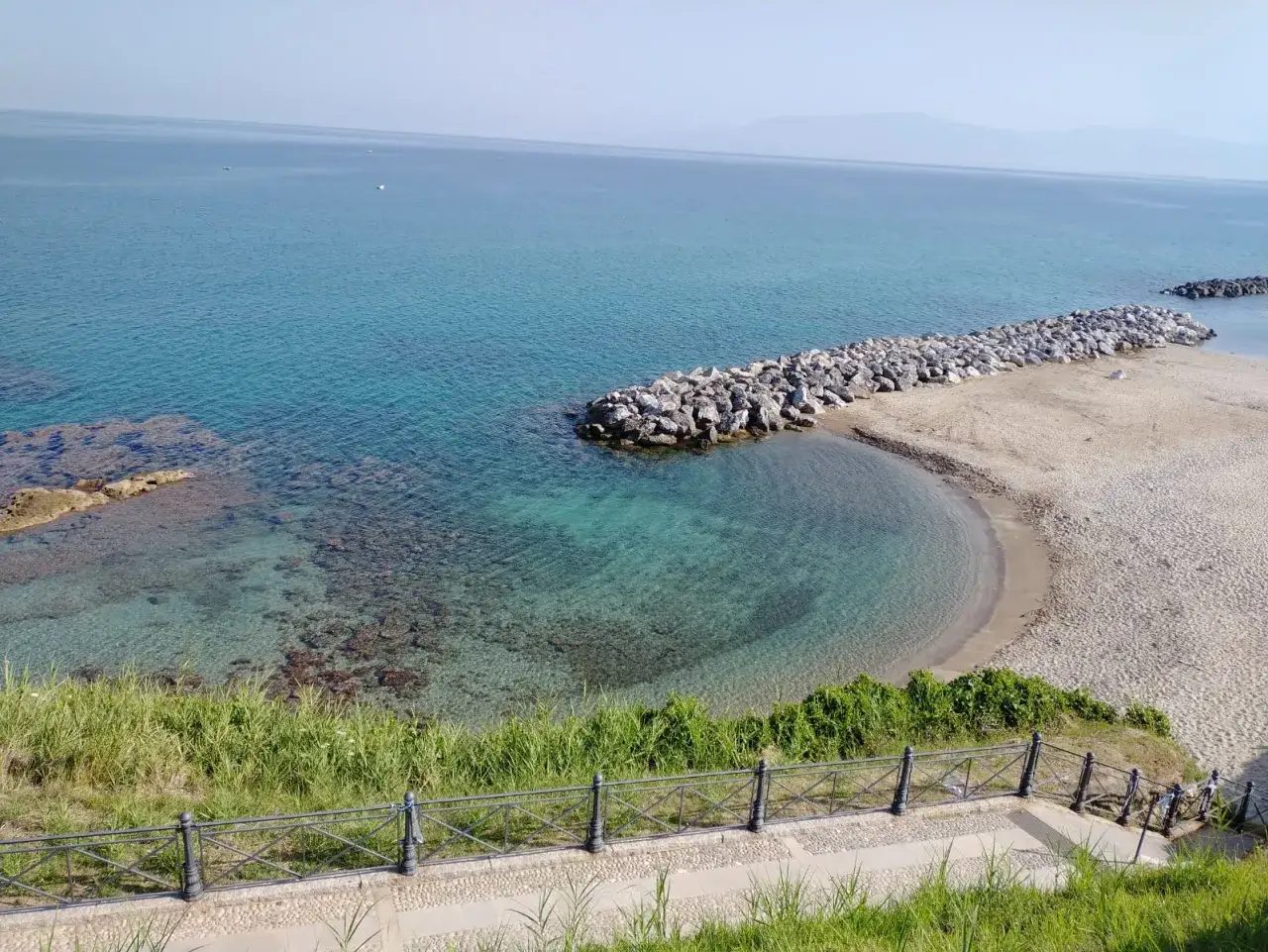 Mare cristallino e spiaggia dorata a Pizzo Calabro, con il centro storico sullo sfondo.