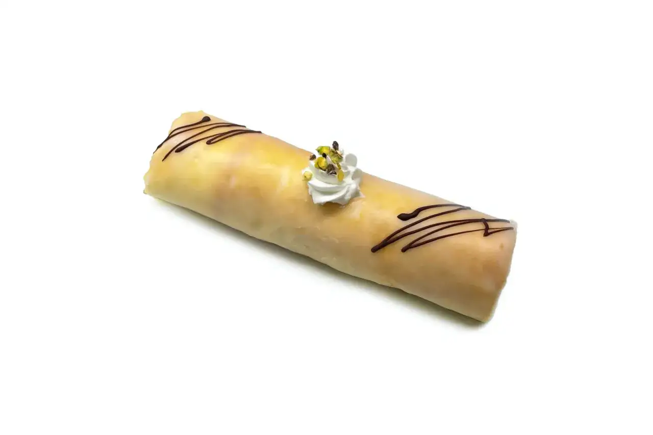 Dolce rotolo glassato con decorazioni di cioccolato e panna montata con pistacchi, un delizioso dito d'apostolo.