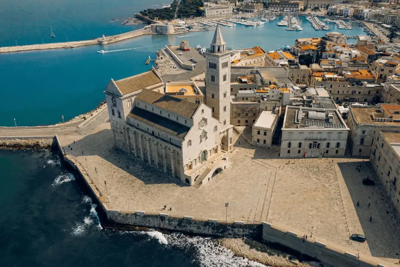La cattedrale domina la piazza del centro storico di Trani, con i suoi vicoli che si perdono tra gli edifici antichi e il mare azzurro.