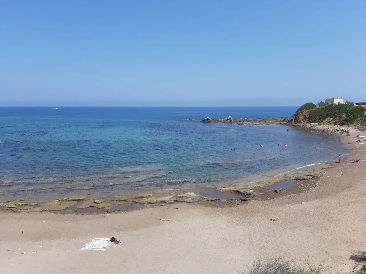 La spiaggia dei Settefrati offre acque cristalline e una baia tranquilla, con bagnanti che si godono il sole e il mare.
