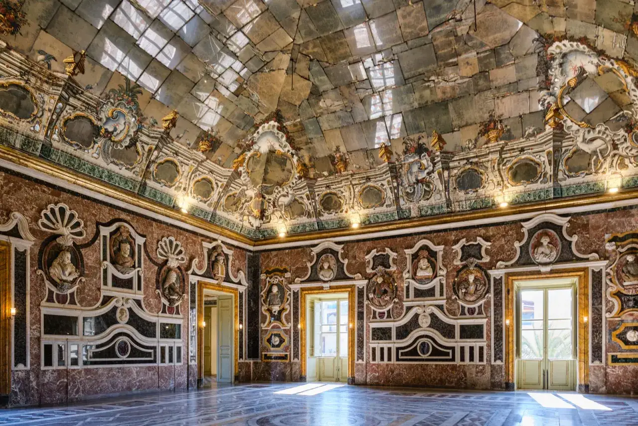 Interno sfarzoso di Palazzo Butera, uno dei luoghi da cosa vedere a Bagheria. Soffitto a specchi e pareti decorate con marmi e busti.
