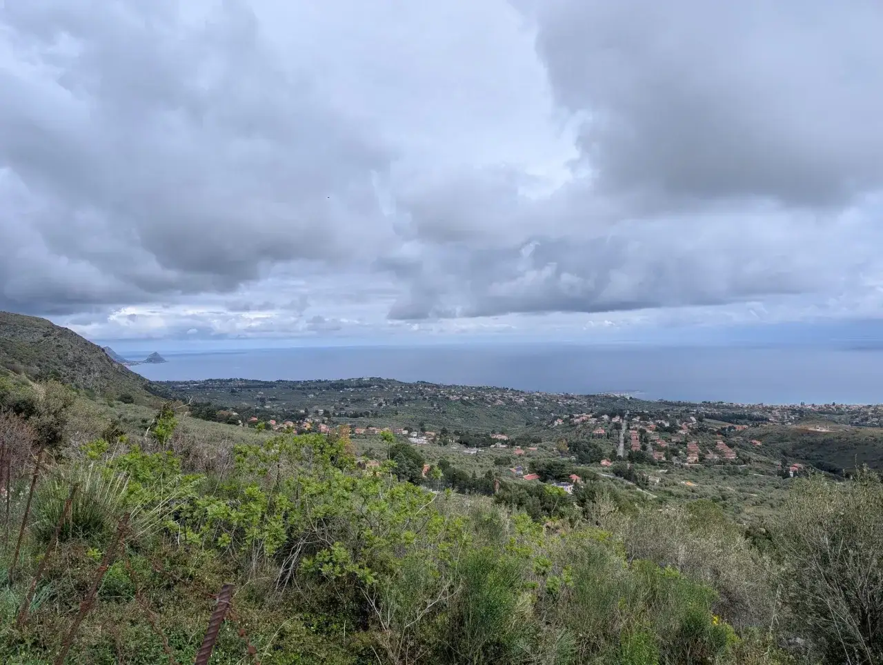 Vista panoramica dal eremo di San Felice con il mare sullo sfondo e un villaggio tra gli ulivi.