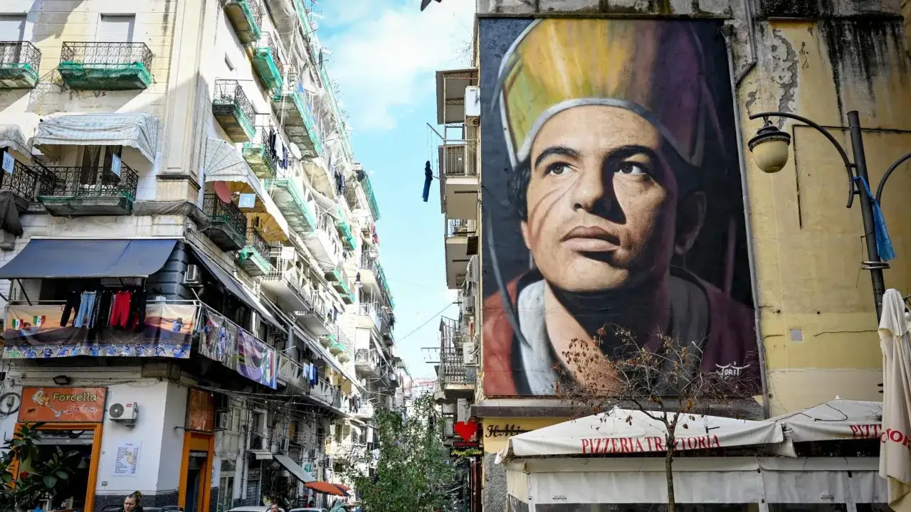 Un imponente murales di San Gennaro domina un vicolo di Forcella, Napoli. La sua figura protettiva veglia sulla vita quotidiana del quartiere.
