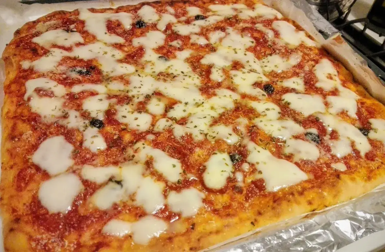 Pizza muddiata appena sfornata, con pomodoro, mozzarella filante e olive nere. Un profumo invitante che fa venire l'acquolina in bocca!