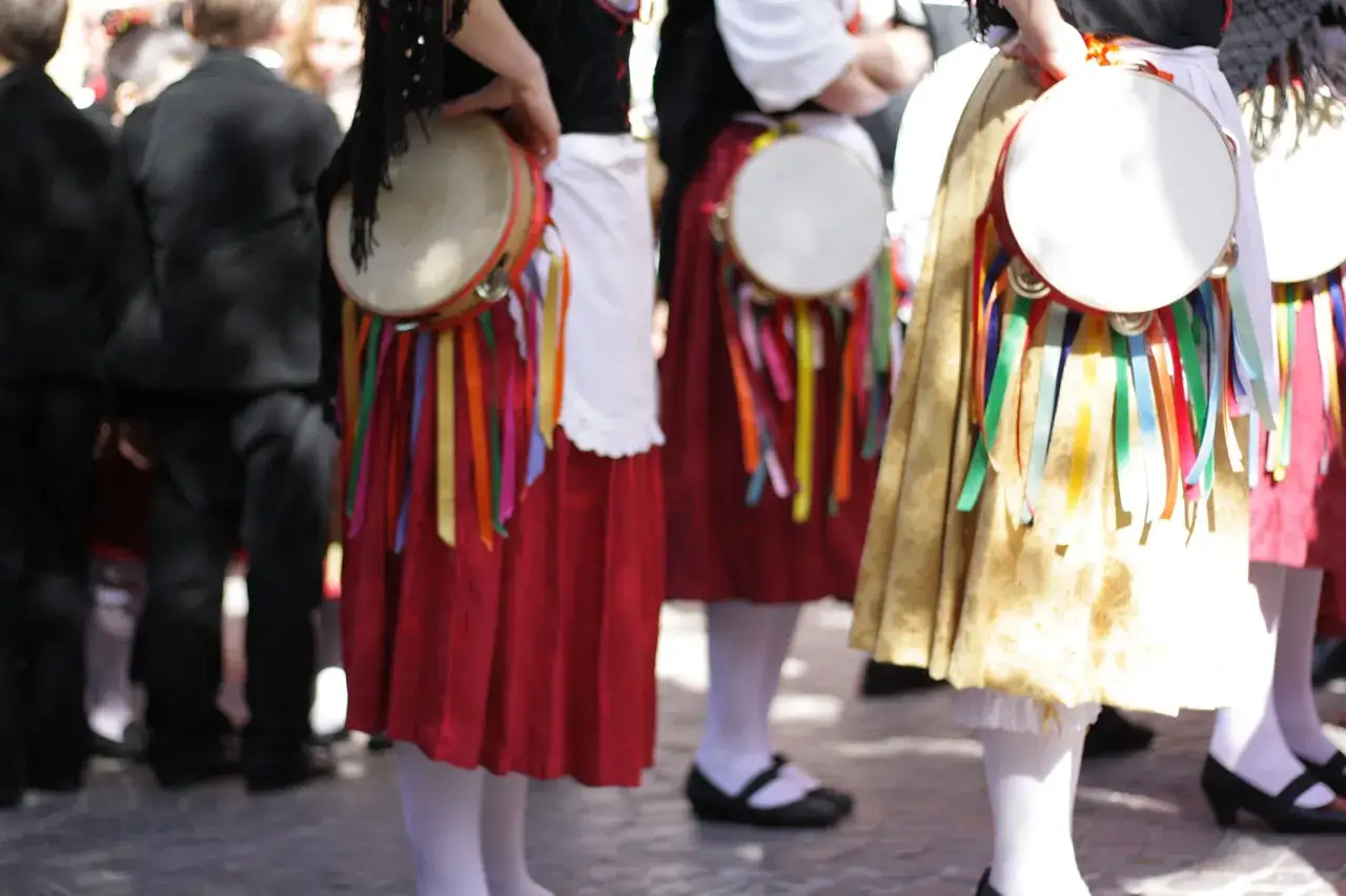 Donne in costume tradizionale con tamburelli e nastri colorati, un'allegra festa di ciuri ciuri.