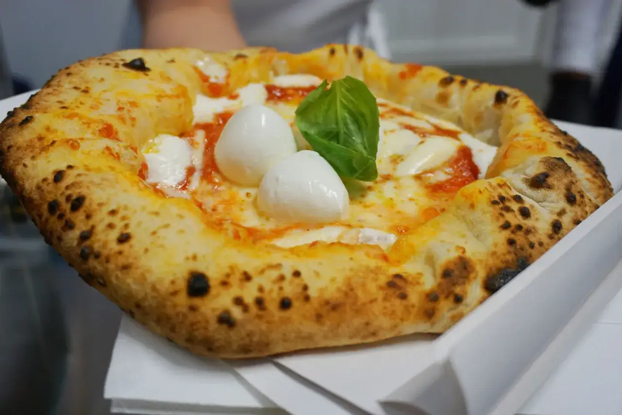 Pizza Margherita, uno dei piatti tipici napoletani, con mozzarella di bufala filante, pomodoro e basilico fresco.